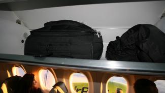 Ручная кладь на багажной полке в салоне самолета